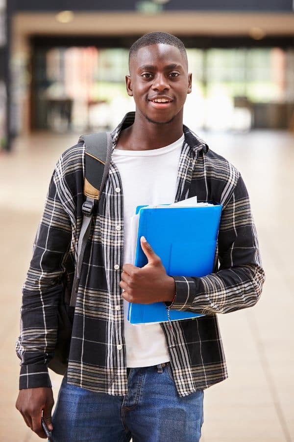 Étudiant souriant avec ses cahiers
